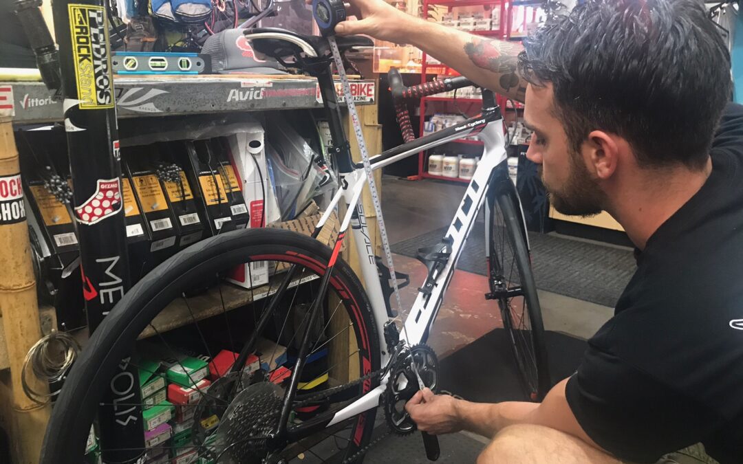 A man repairing a bicycle in a store, focusing on fixing the gears and adjusting the brakes.